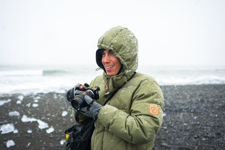 Man in puffy jacket with camera on beach