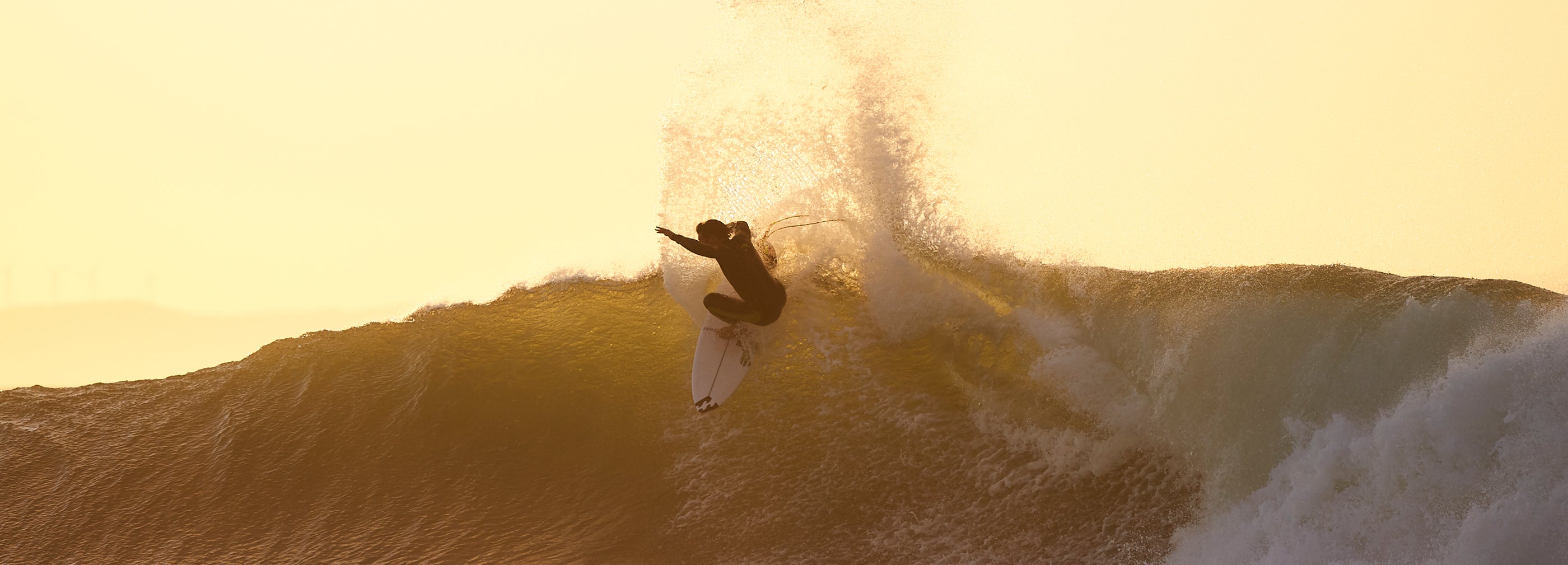 Person catching wave at sunset