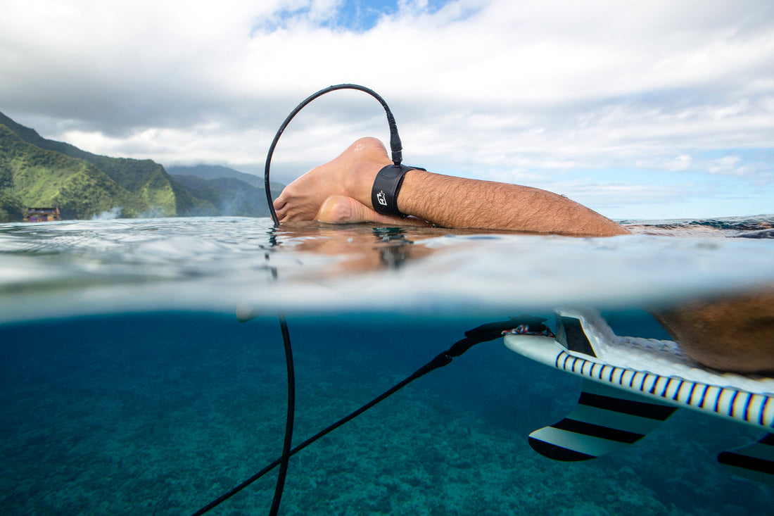 Feet with surf leash attached half in and half out of water