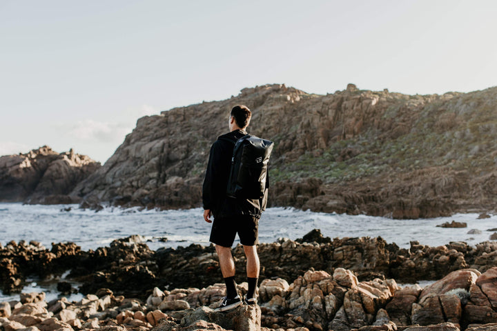 Man standing on rocky beach looking at ocean