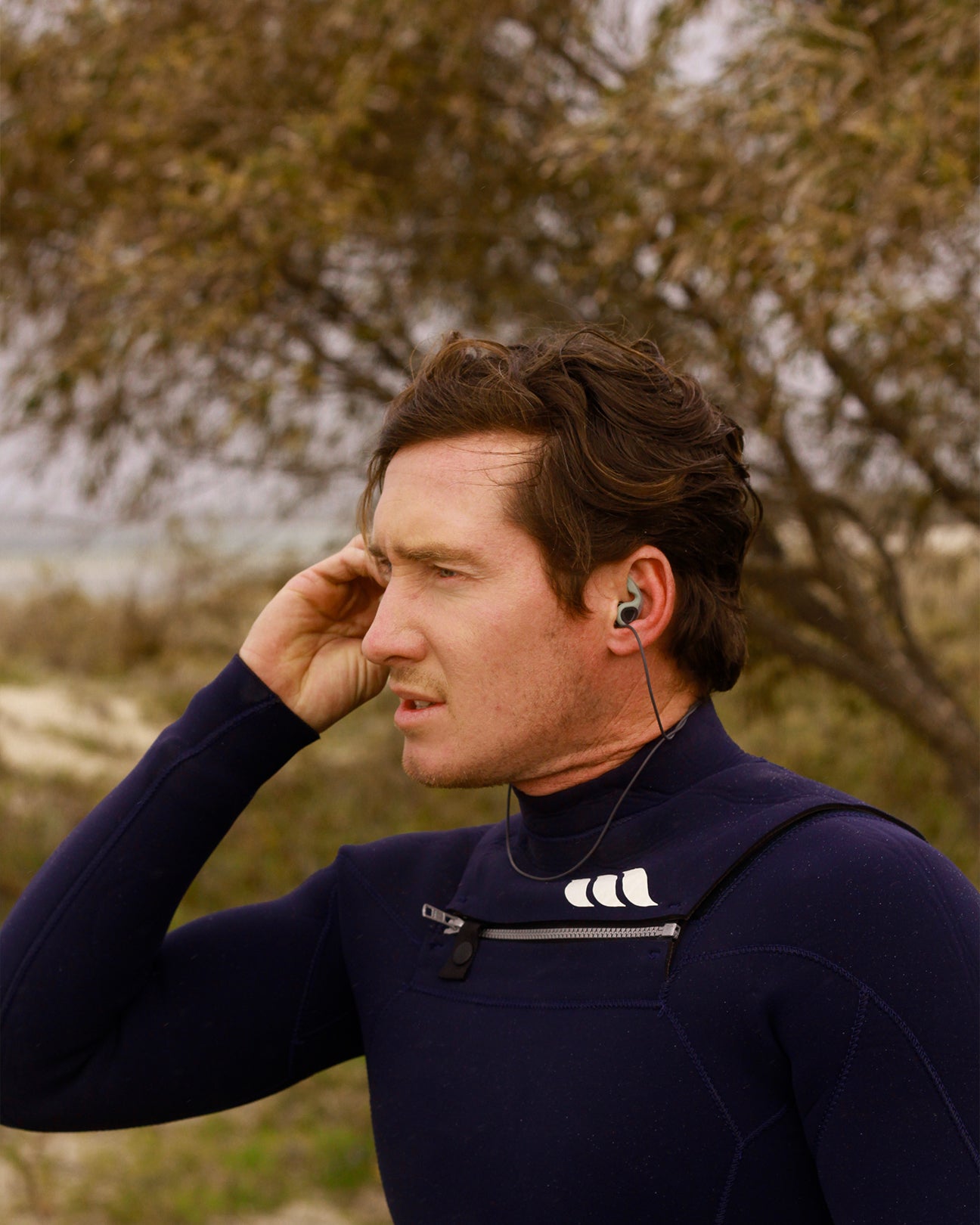 Smiling man putting surf ear plugs in