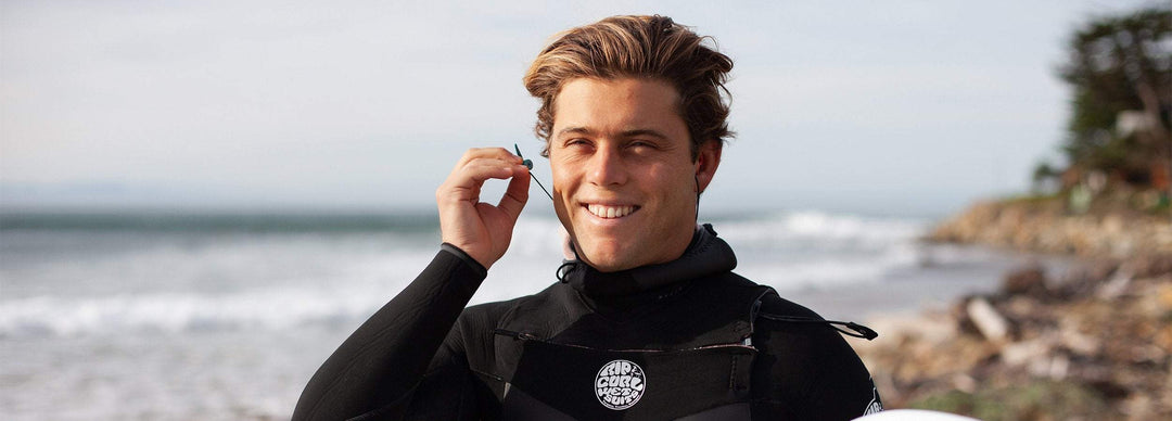 Smiling man putting surf ear plugs in