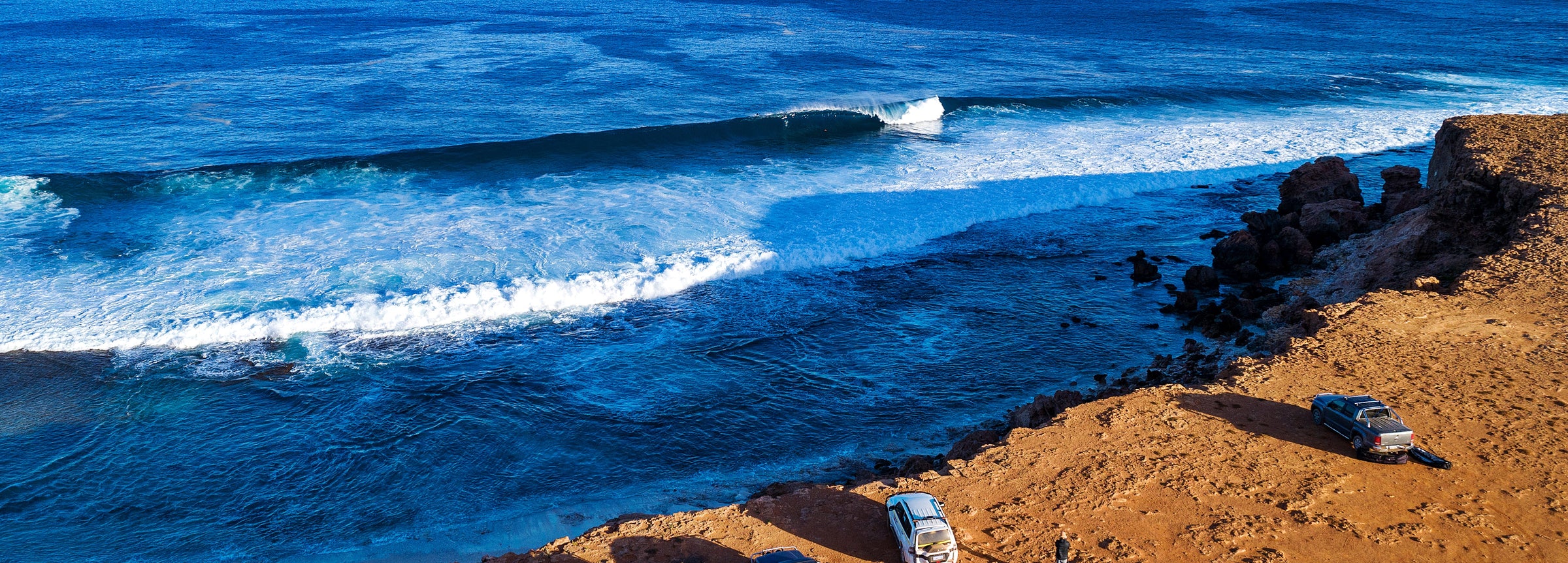 Orange sand beach meeting blue ocean with waves crashing on beach